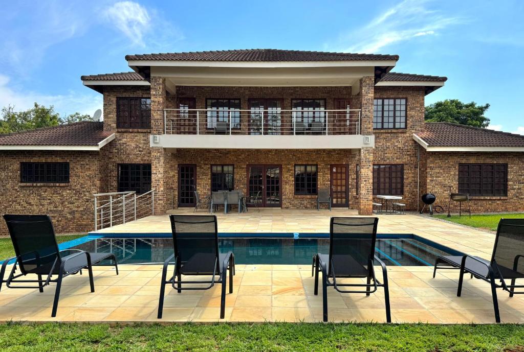 a house with a pool and chairs in front of it at Avocado Grove Guest House in White River