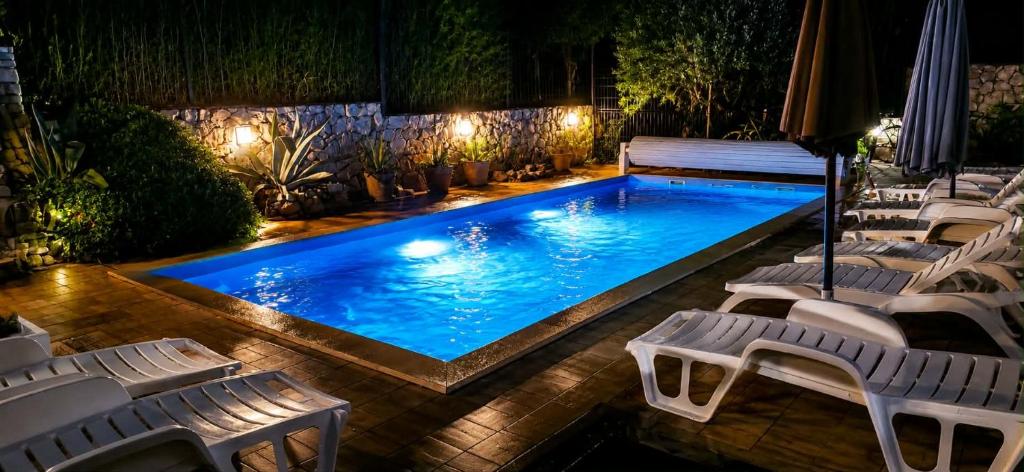 a swimming pool with white chairs and a group ofigators at VODICE KRAJE APARTMENTS in Vodice