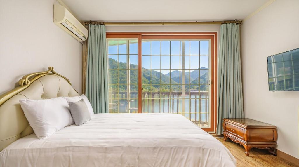a bedroom with a bed and a large window at Gapyeong Elin Pension in Gapyeong