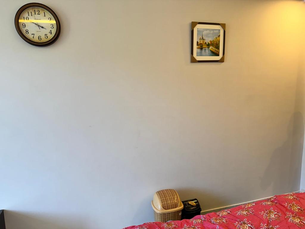 a clock on a wall next to a bed at Swiss Suits, Suit 407 in Taiwāl