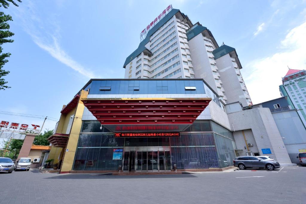 a building in a city with cars parked in a parking lot at Golden Inns Beijing South Railway金泰之家北京南站店 in Beijing