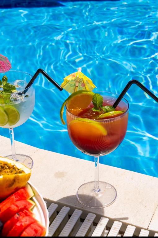 two cocktails sitting on a table next to a swimming pool at El Candelabro in Pisco