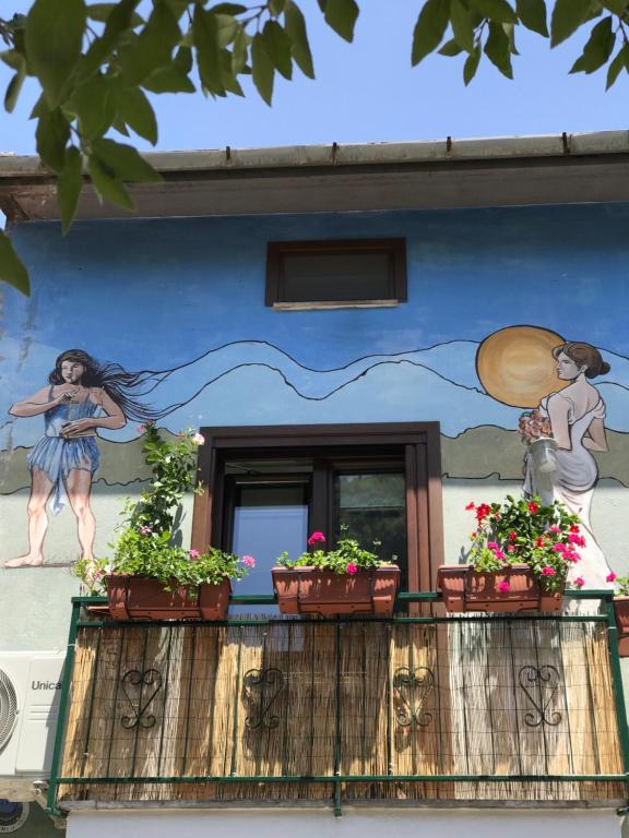 a mural on a building with plants on a balcony at Casa Vacanza Finalmente in SantʼAngelo le Fratte