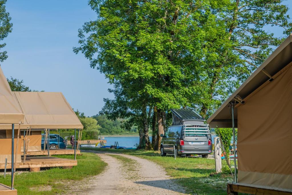 a campsite with a truck parked next to a tree at Camping Onlycamp Les Peupliers in Lepin-le-Lac