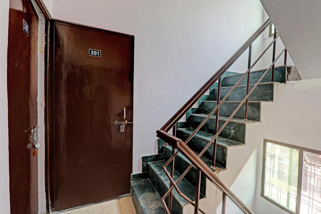 a hallway with a staircase with a wooden door and a stair case at Hotel O Raama in Lucknow