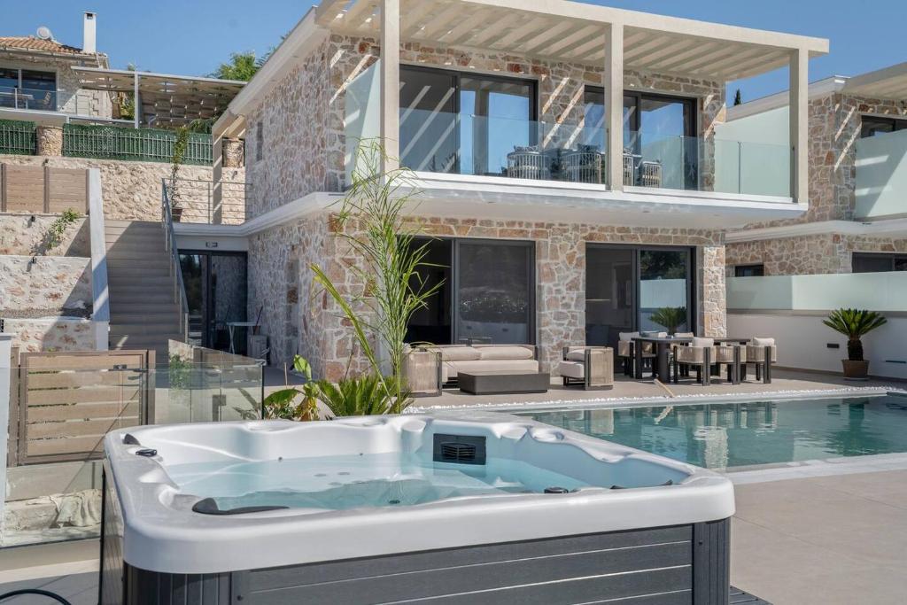 a bath tub in front of a house with a swimming pool at Goudis Luxury Villas Lefkada Sea View & Private Pools in Tsoukalades