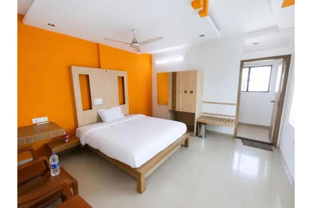 a bedroom with a white bed and an orange wall at FabHotel Bhagyashri Executive in Nashik