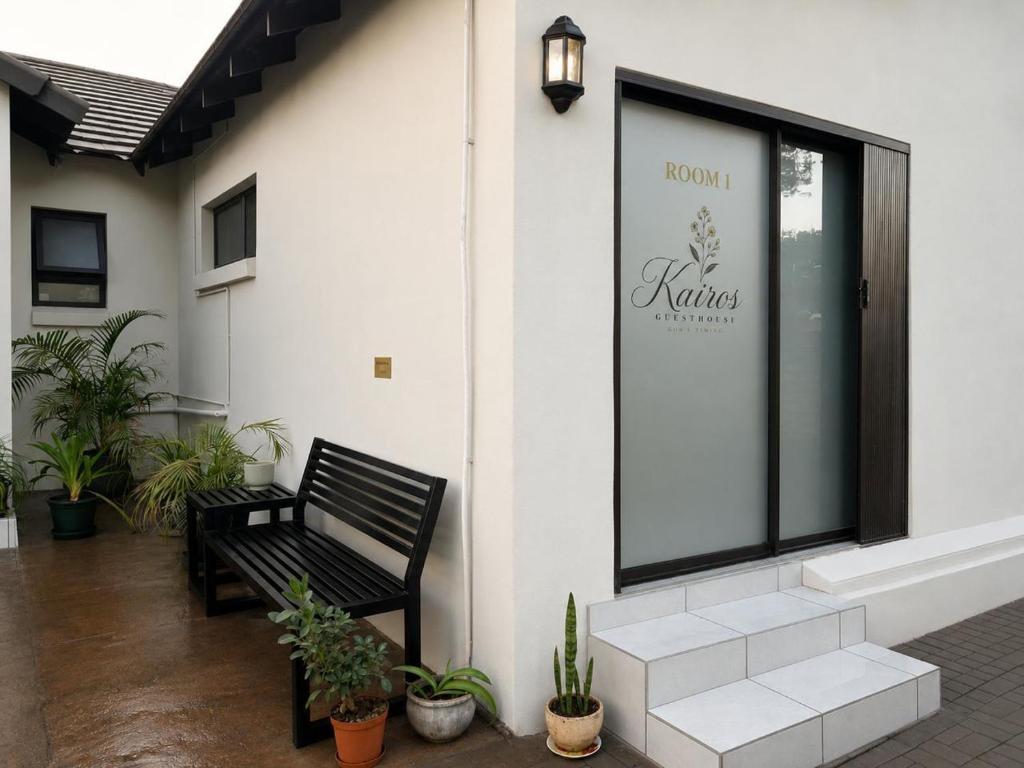 a black bench sitting outside of a building with plants at Kairos Guesthouse in Thabazimbi
