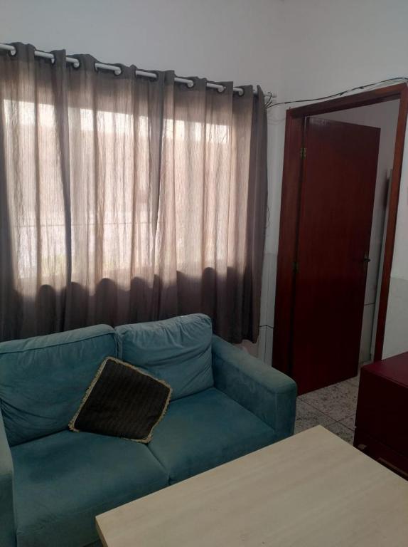 a blue couch in a living room with a window at Casa no centro - perto de tudo in Itaguaí