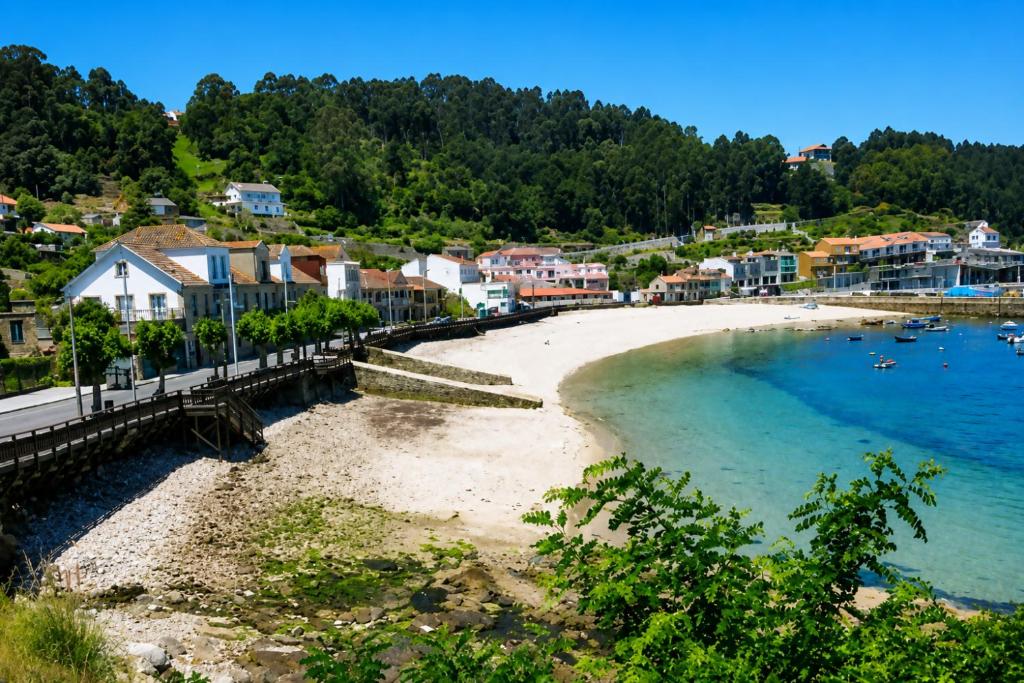 a beach in a town next to the water at Casa baja a la playa in Bueu