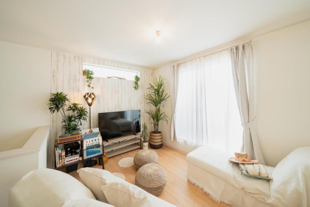 a living room with a couch and a tv at 照間Terumaの美しい海と太陽 Soleが目前に広がる和室ありの宿 TERUSOLEテルソーレ in Uruma