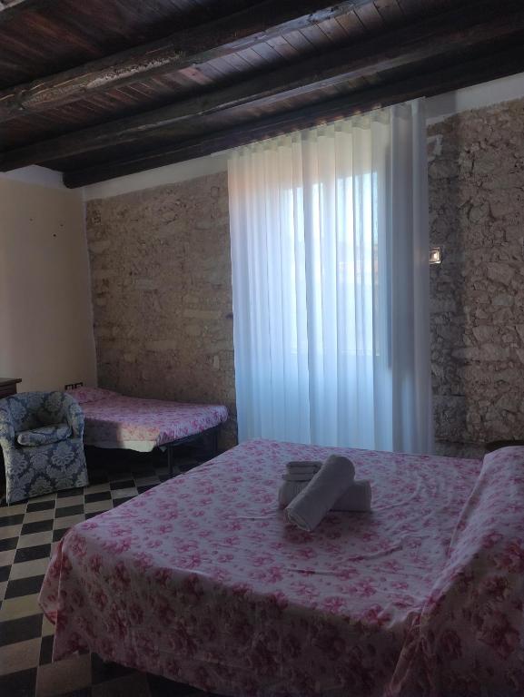 a bedroom with two beds with pink sheets and a window at Affittacamere Isidoro in Zaccanopoli