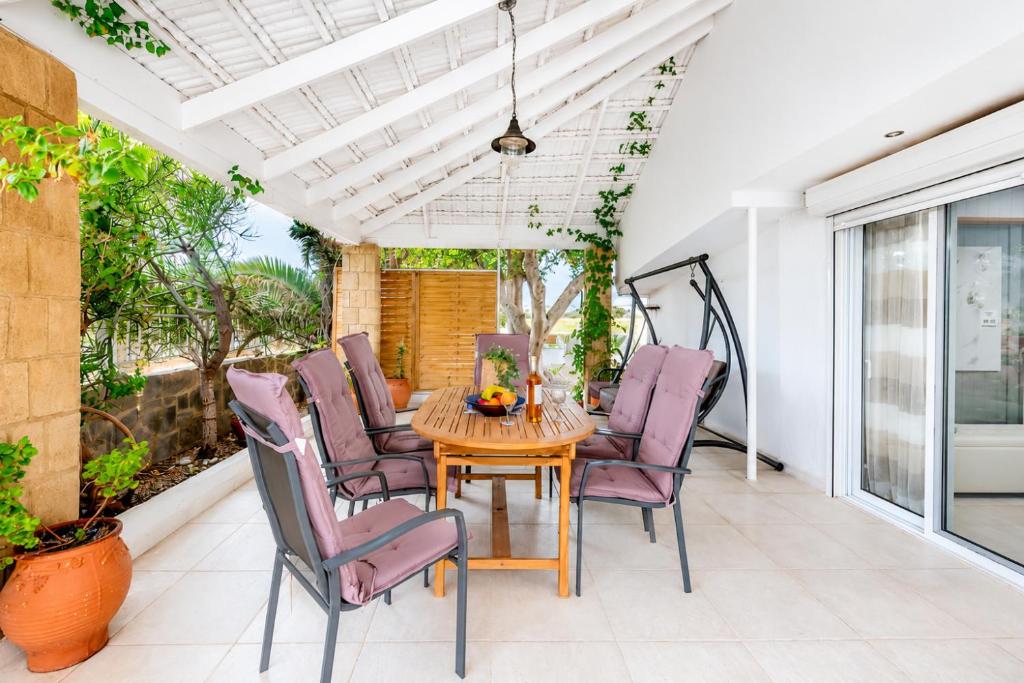 a patio with a wooden table and purple chairs at Beach House Cavo Kiotari in Gennadi