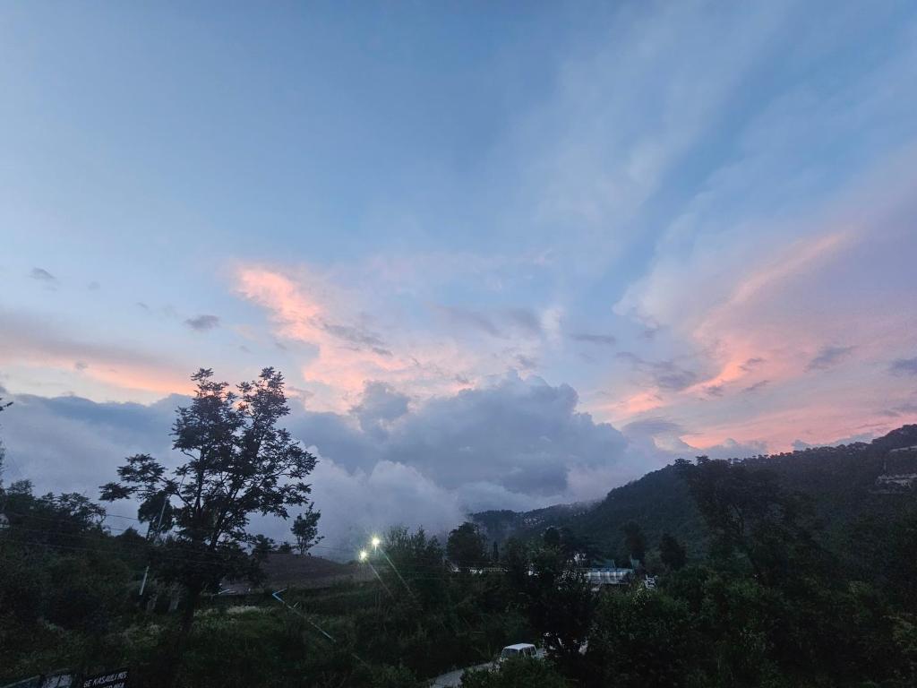 a cloudy sky with a view of a mountain at The Sanmit Stay Kasauli by Splendid Retreat Hotels in Kasauli