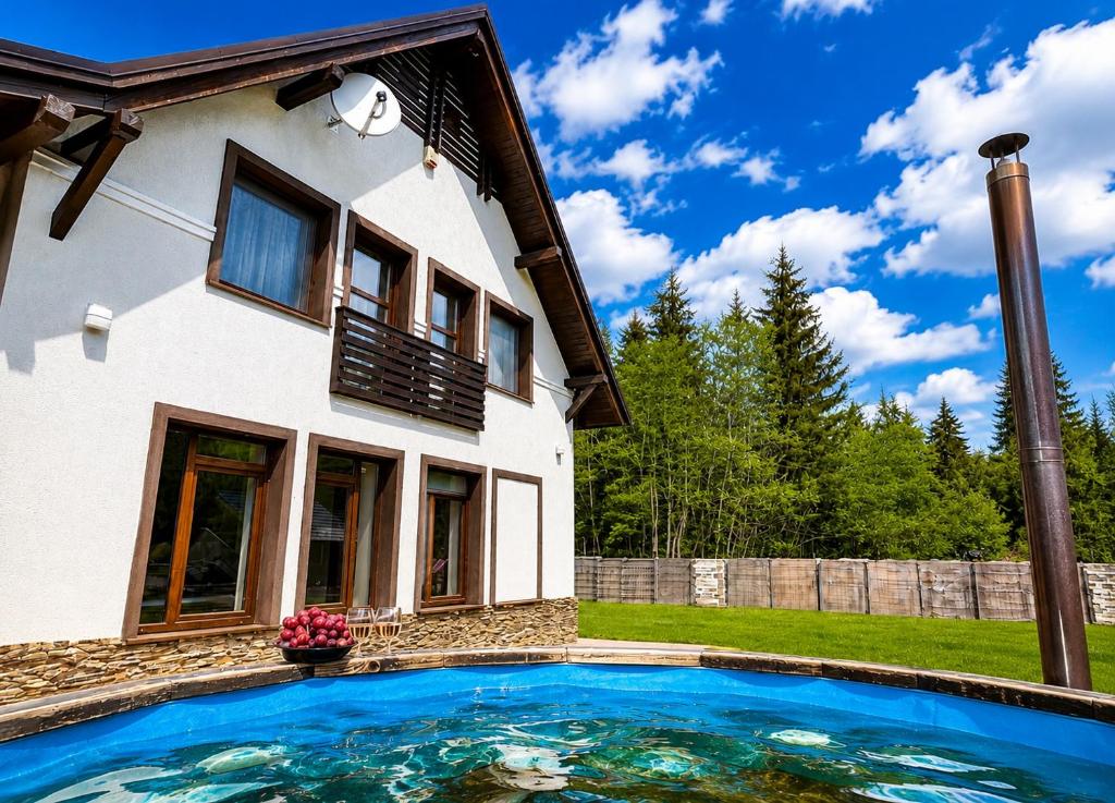a swimming pool in front of a house at Mountain Paradise & Wellness in Izvoare