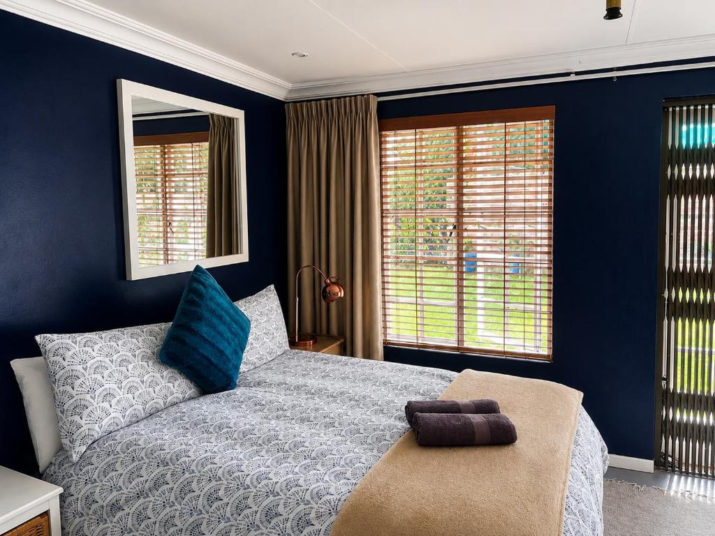 a bedroom with a bed with blue walls and windows at Limonite Guesthouse in Pretoria