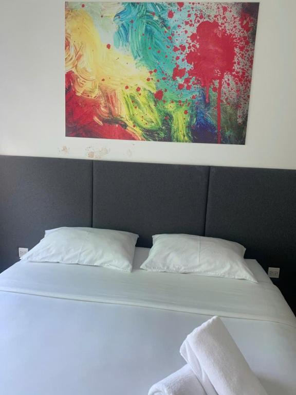 a bed with two pillows and a painting above it at ARVO Cam Ranh - Infinity swimming pool in Cam Ranh International Airport