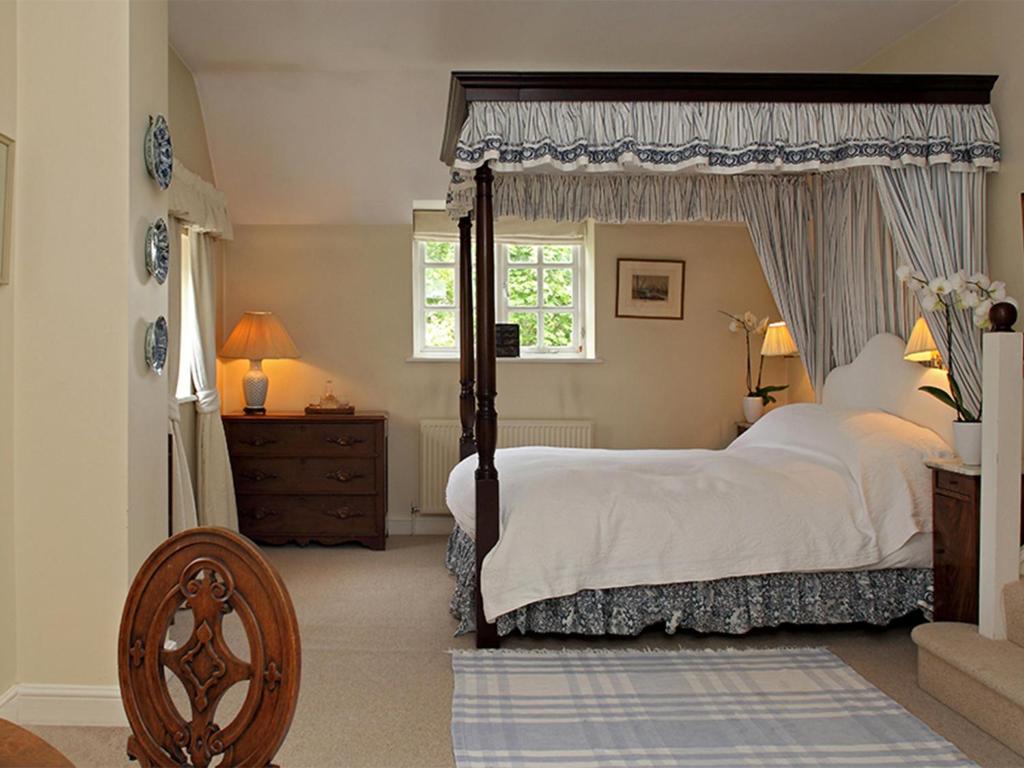 a bedroom with a canopy bed and a window at Aintree Cottage in Bruern