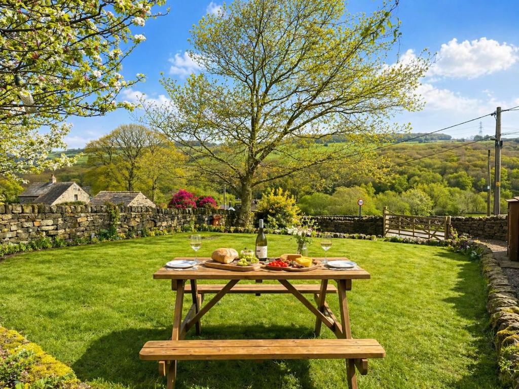 a picnic table in the grass with a bottle of wine at The Old Smithy in Langsett
