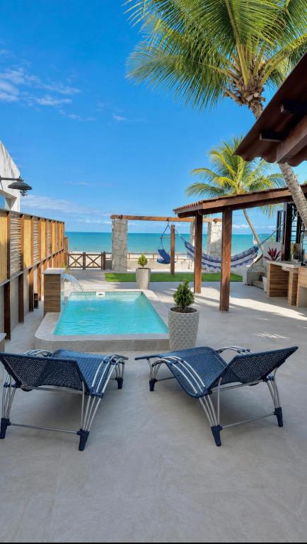 a patio with two chairs and a swimming pool at Brisa de Barra Grande Beach House Pé na Areia in Maragogi