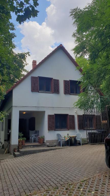 a white house with windows and chairs on a driveway at Winterberg Vendégház in Óbánya