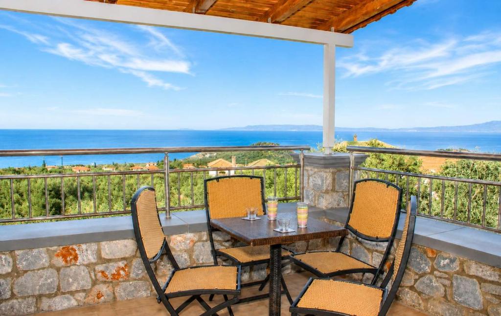 a table and chairs on a balcony with a view of the ocean at Emilia's Guest House with Sea View Balcony, Stoupa in Stoupa