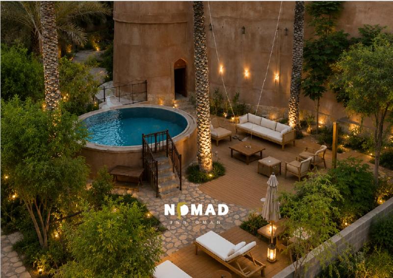 an overhead view of a patio with a pool with palm trees at Nomad Inn Al Bustan in Nizwa