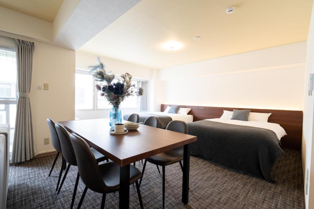 a hotel room with a table and two beds at Residence Hotel KABUTO Premier in Sapporo