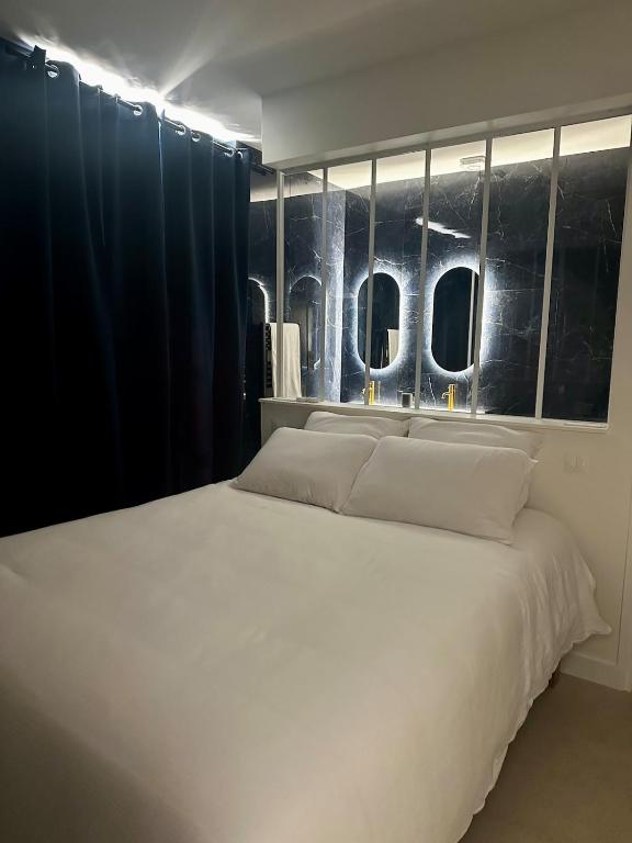 a bedroom with a large white bed with windows at La Nuit Etoilee Balneo Hyper Centre Chalon in Chalon-sur-Saône