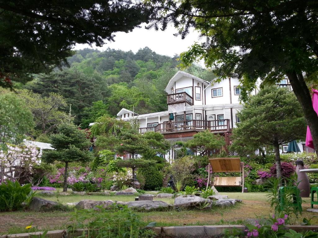 a large white house with a garden in front of it at Starvill Pension in Pyeongchang