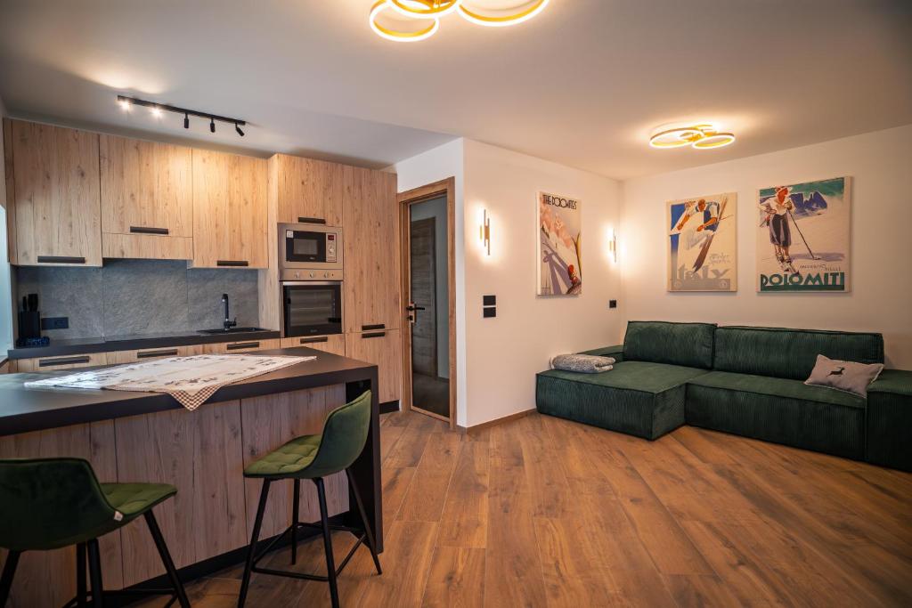 a living room with a green couch and a kitchen at La Stua de Anny by AMA Val di Fassa in Pozza di Fassa