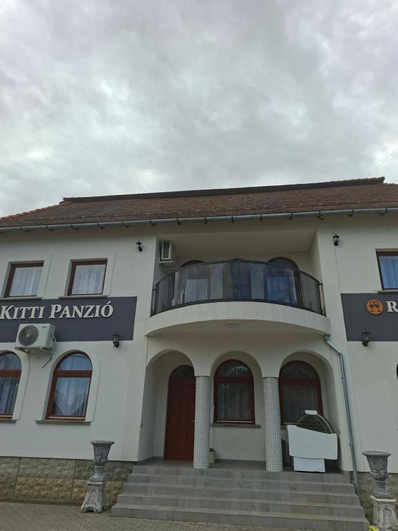 a building with a balcony in front of it at Kitti Panzió in Tiszadada