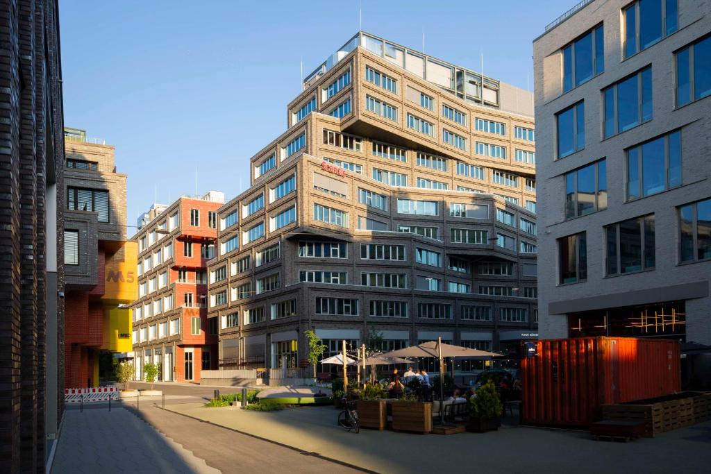 a tall building with a cafe in front of it at Scandic München Macherei in Munich