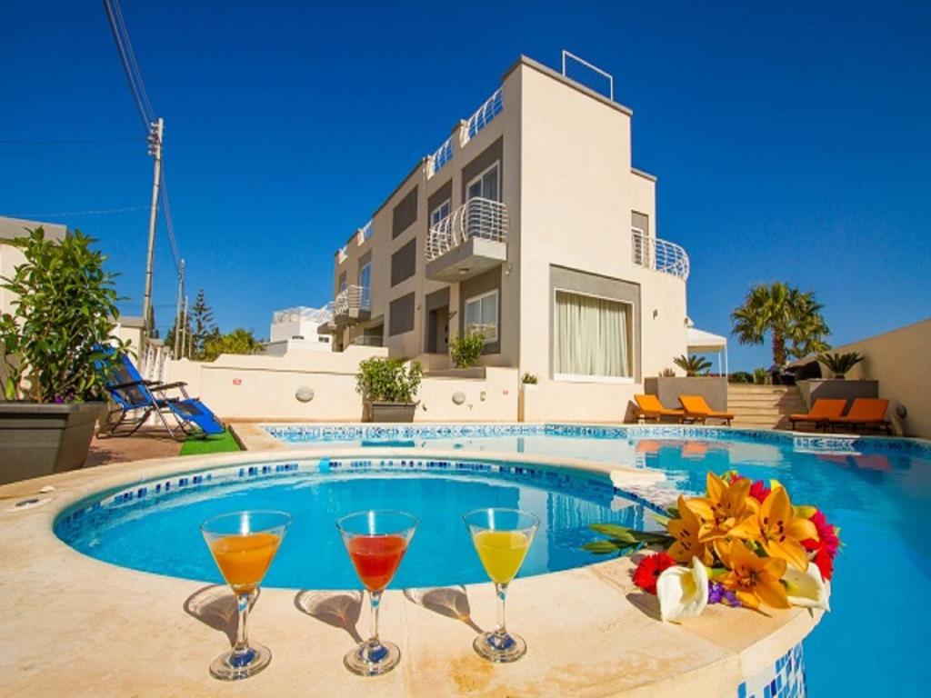 a swimming pool with two glasses of wine at Villa Diamantina in St. Julianʼs