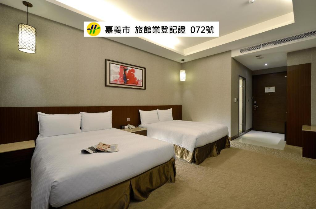 a hotel room with two beds and a window at Guanko Hotel in Chiayi City
