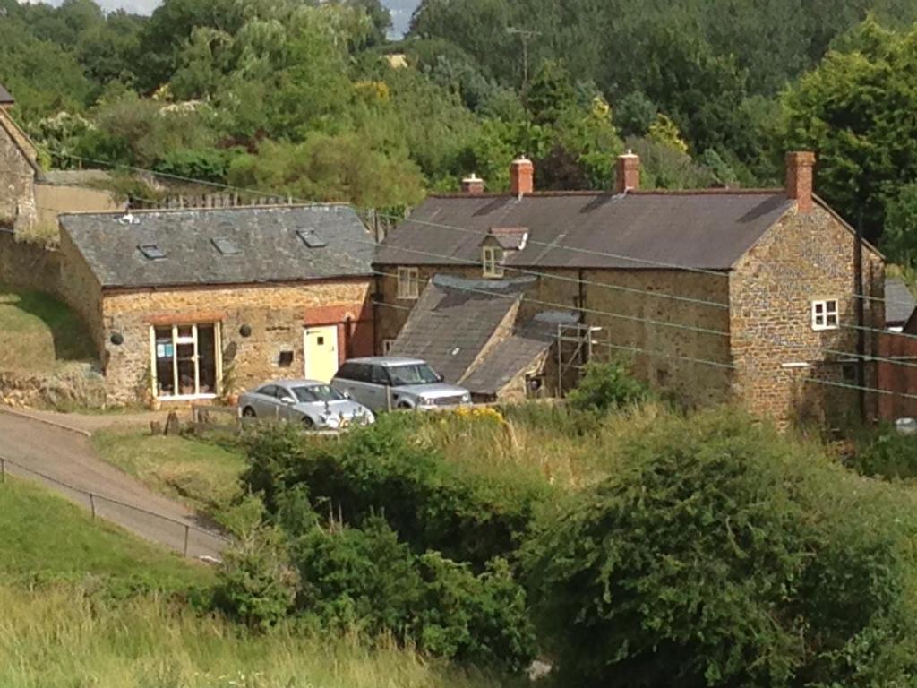 deux voitures garées devant un bâtiment en briques dans l'établissement Holly Cottage, à Banbury