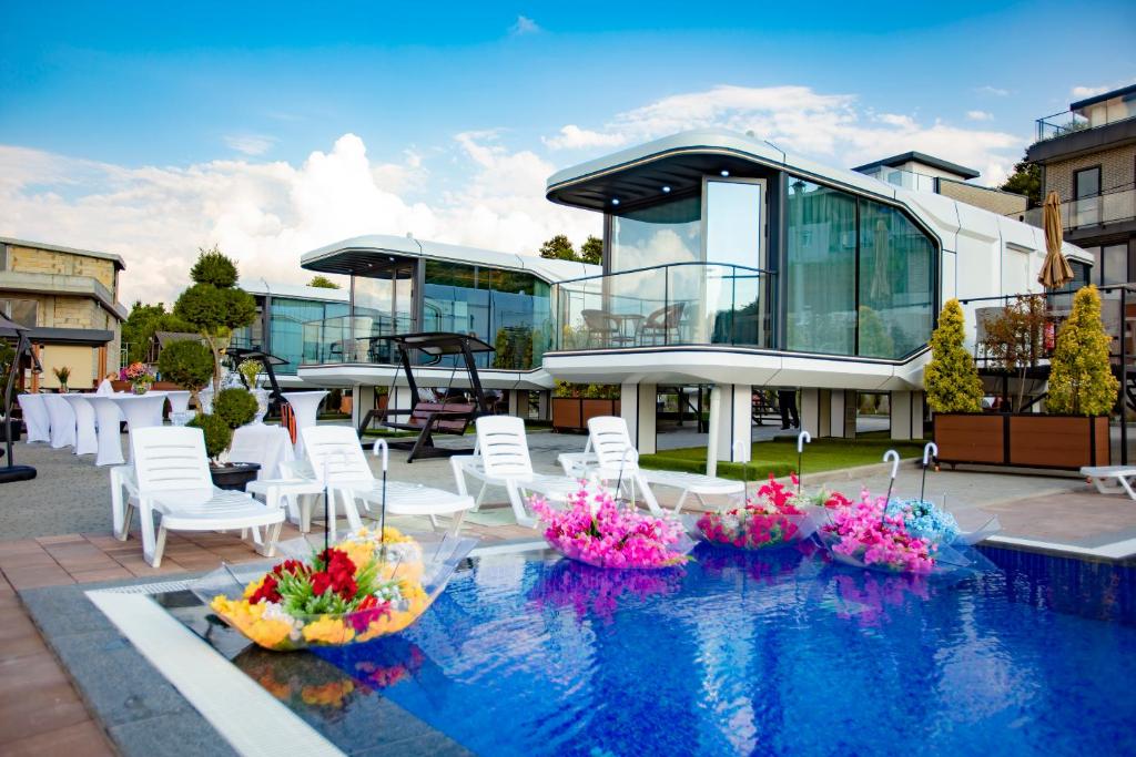 a house with a swimming pool with white chairs and flowers at Mars Oasis Capsule in Charnali