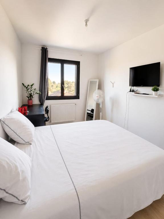 a white bedroom with a large white bed and a television at Beautiful, modern room in Saint-Paul-de-Varax