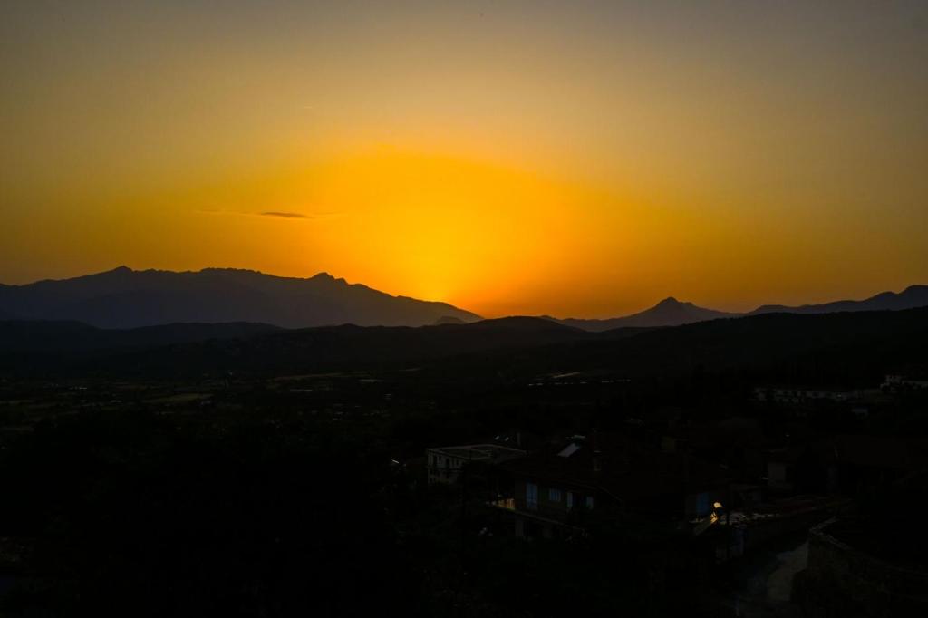 a sunset over a city with mountains in the background at Sunset Stories Apartments in Konitsa