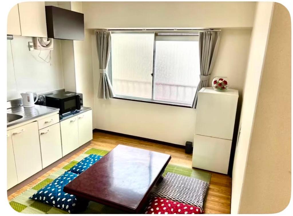 a small kitchen with a table and a refrigerator at パールビル201 in Osaka