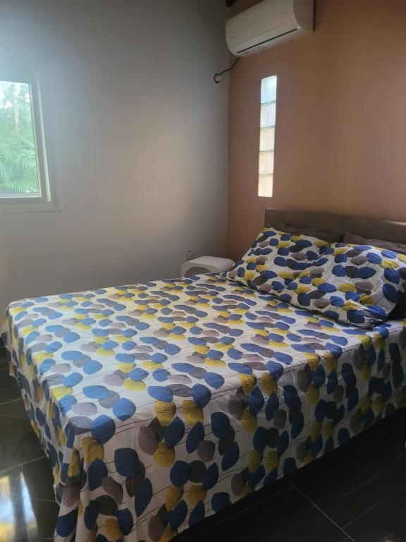 a bedroom with a bed with a blue and yellow comforter at Entre terre et ciel in Baie-Mahault