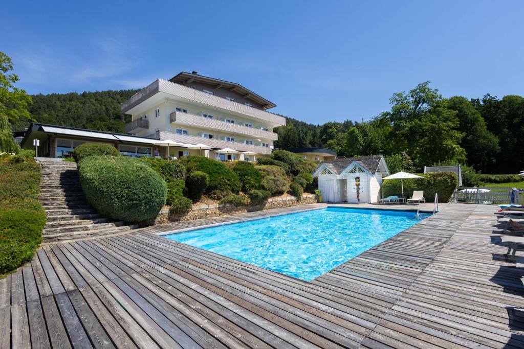 a house with a swimming pool and a wooden deck at Hotel Garni Wurzer in Velden am Wörthersee