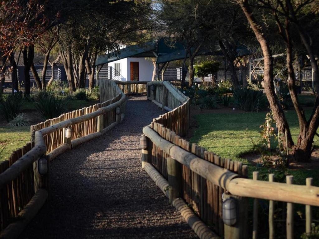 a wooden fence in front of a yard with trees at Meloding Guest House in Bela-Bela