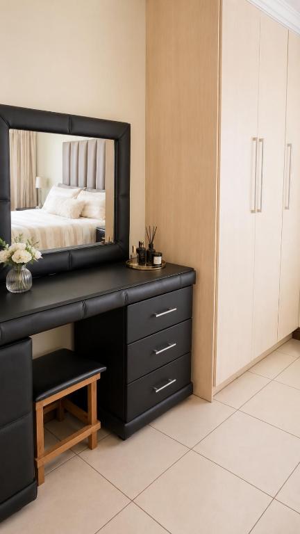 a bedroom with a desk with a mirror on it at Azania Bed & Breakfast in Meyerton