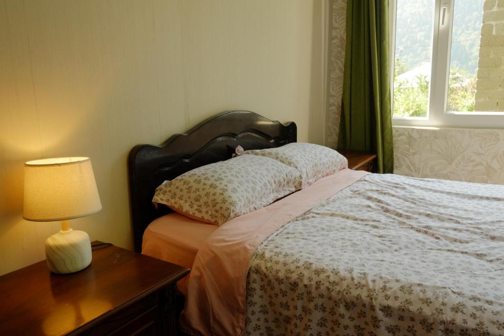 a bedroom with a bed with a lamp and a window at Svaneti Heaven in Lentekhi