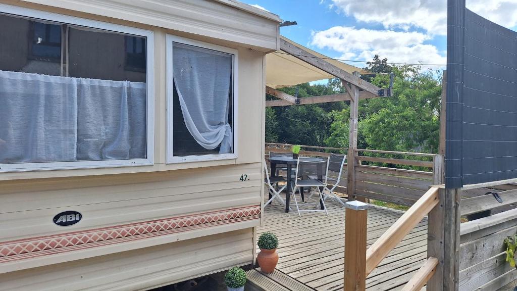 a house with a porch and a table on a deck at Mobile-home 4, 6 places in Quédillac