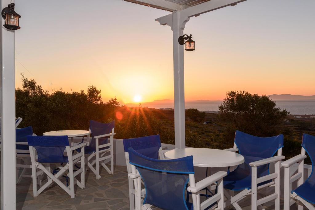 a patio with tables and chairs with the sunset in the background at Unique Galini Oia - Adults Only in Oia