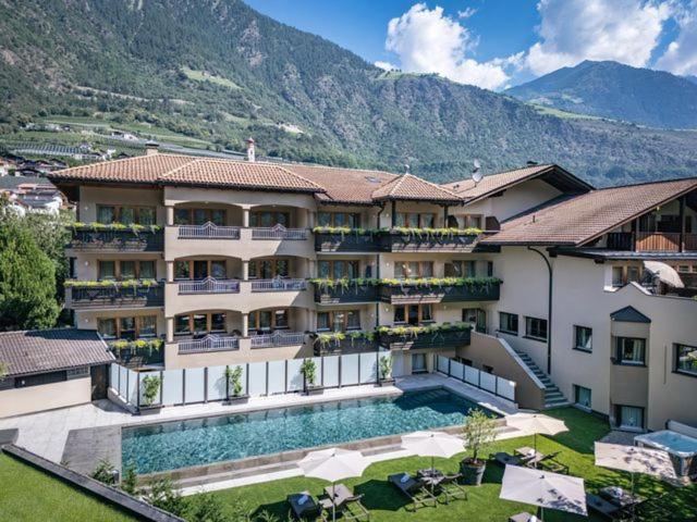a large building with a swimming pool next to a mountain at Hotel Kesslwirt in Ciardes