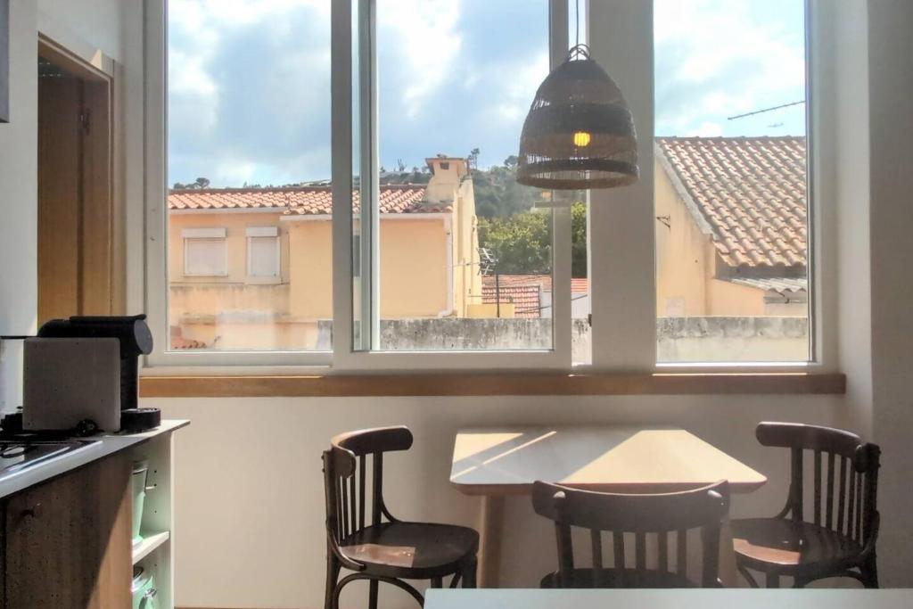 a kitchen with a table and chairs and a window at Lisbon, beach, city & surf in Trafaria