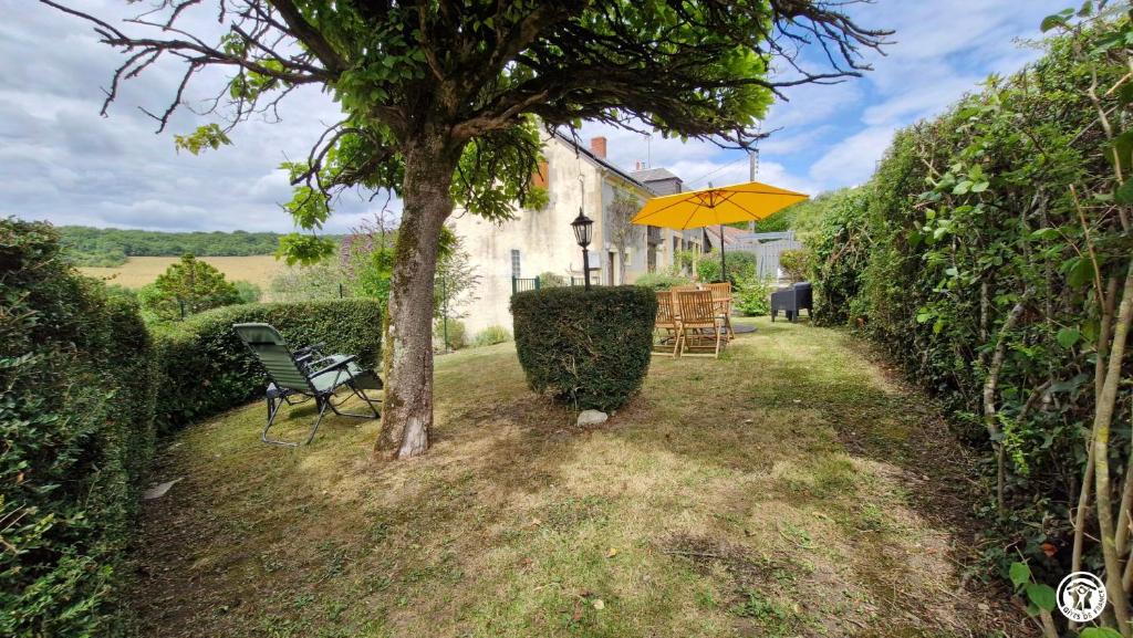 a yellow umbrella and a chair under a tree at Gîte de L'Abbaye in Nolay